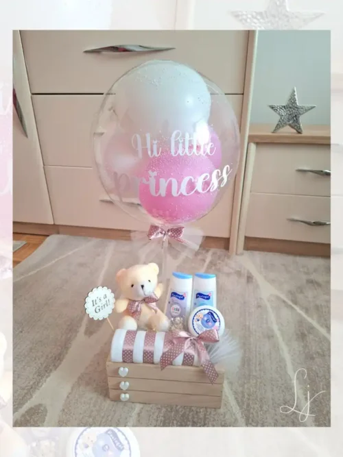 Roze poklon set za devojčicu u drvenoj gajbici sa personalizovanim balonom, plišanim medom i bebi kozmetikom.